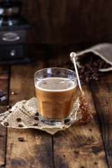 Glass of hot coffee with milk on wooden table