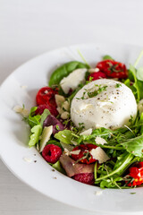 Salad with Italian burrata cheese, arugula, cherry tomatoes, parmesan and raspberry