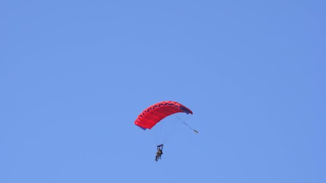 Tandem parachute jump. Silhouette of skydiver flying in blue clear sky. Concepts of extreme sport and adrenaline.