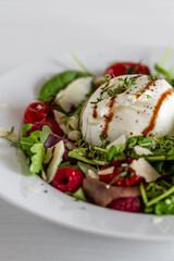 Salad with Italian burrata cheese, arugula, cherry tomatoes, parmesan and raspberry with balsamic glaze