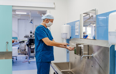 Surgeon in hospital washing thoroughly his hands before performing a surgery. Doctor washing hands before operation.