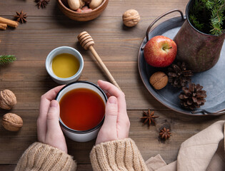 Hands keep cup of  aroma  Christmas Apple tea with cinnamon on a wooden table