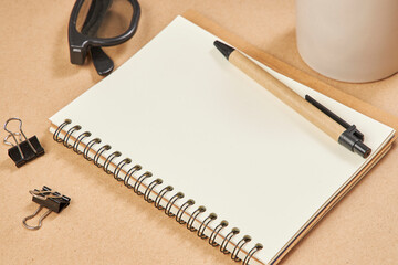 Top view of a desk mockup: blank paper list and pen, coffee cup on a beige background