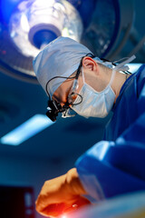 Neurosurgeon in operation room. Attentive doctor in surgical glasses provides operation. Selective...