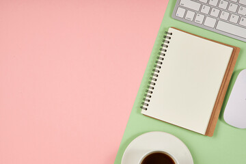Pink and green office desktop. Top view table with notepad, keyboard. Mock up, copy space.