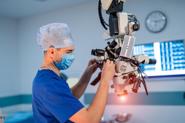 Neurosurgeon with surgery microscope in operating room. Experienced neurosurgeon in modern clinic.