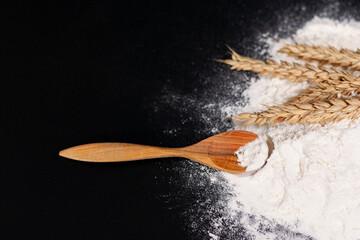 On the right side of the screen, a bunch of wheat spikelets and a wooden spoon are placed on a pile of white flour.