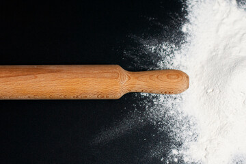 To the right, on the dark surface of the table, is a mound of white flour. In the center is a...