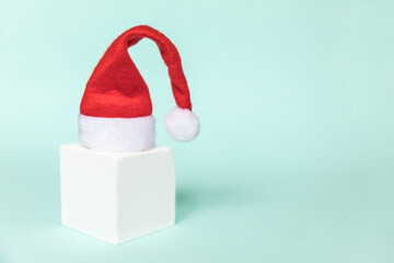 Simply minimal composition winter object Santa hat and cube shapes geometric form podium isolated blue pastel background. Christmas New Year december time for celebration concept. Mockup, copy space