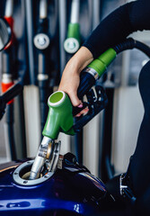 Modern motorcycle is fueling with petrol. A gas station's store. Stand with pistols.