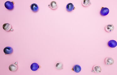 Christmas balls for decoration in blue and silver on a pink background on the edges in the form of a frame. Free space for text, top view.
