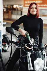 Naklejka na ściany i meble Positive girl sitting on her expensive urban bike. Custom sport motorcycle and its female owner. Vintage photo of refueling.