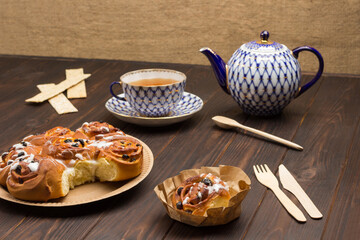 Raisin buns in cardboard plate. Teapot and cup of tea