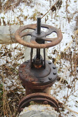 Fototapeta premium Old damaged and rusty iron oil pipe valve wheel. Metal, pipeline and mechanic concept. An old iron valve on a gas pipe. A valve to cover the pipe with a round handle