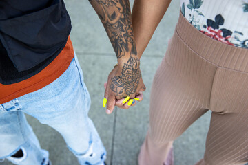 Close up detail of tattooed hand holding with two women outside