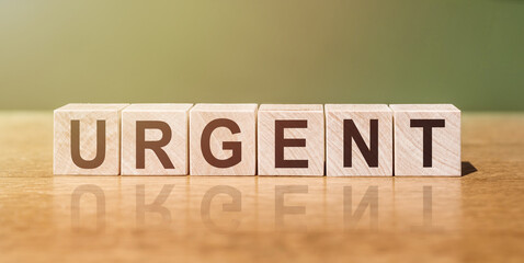 The word URGENT on wooden cubes on a table, on a beautiful background.