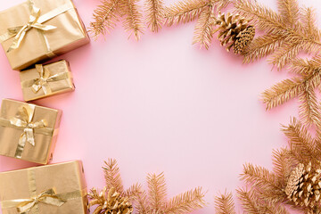 Fototapeta na wymiar Pink Christmas or new year's background,plain composition of golden Christmas gifts and golden fir branches with christmas toys,Flatlay,empty space for greeting text.christmas concept.