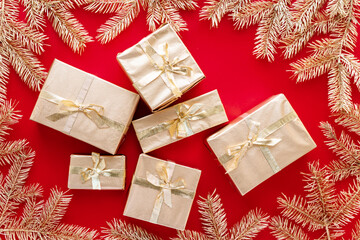 Red Christmas or new year's background,plain composition of golden Christmas gifts and golden fir branches, Flatlay,empty space for greeting text.christmas concept.