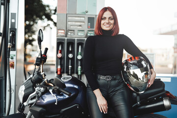 A joyful female biker enjoying her motorcycle. A modern bike and its female owner in the refueling....