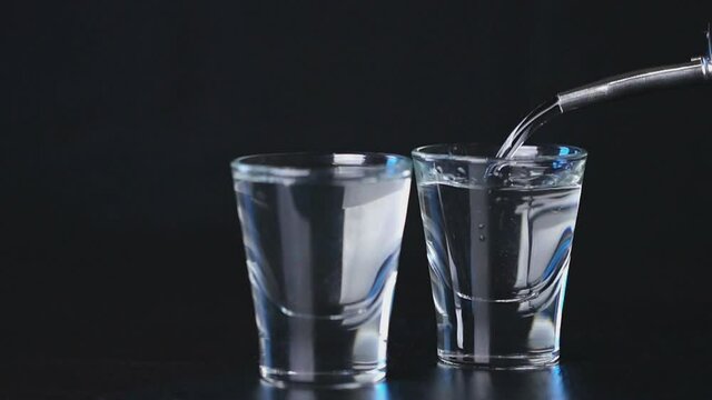 cinemagraph, vodka is poured into a glass on black background