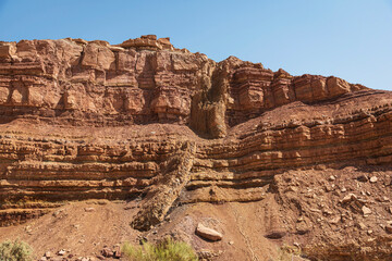 a diagonal magmatic igneous dike cuts through red and orange horizontal layers of limestone in...