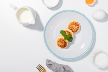 Cottage cheese, eggs, cream and yougurt on a white background - Flat lay with curd pancake - Recipe