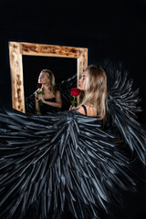 Obraz premium handsome muscular man in angel costume with black wings and fragile defenseless beautiful girl in white