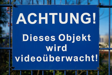  blaues Schild mit der Aufschrift "Achtung, dieses Objekt wird videoüberwacht"