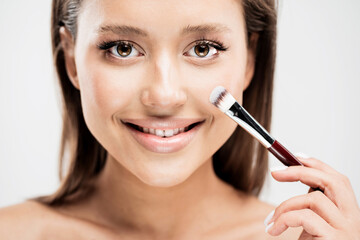 European appearance close portrait of a beautiful face, a woman applies powder toning effect cosmetics professional on the skin.