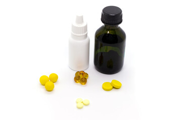 Yellow pills, bottle with brilliant green, nasal drops for the common cold on white background.
