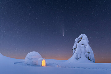 Snow igloo luminous from the inside in the winter mountains. Starry sky with comet on the background - obrazy, fototapety, plakaty