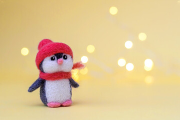 Toy wool penguin on a yellow background with bokeh