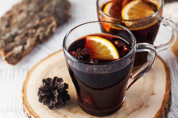 Mulled wine in mugs with star anise and orange on a wooden stand.