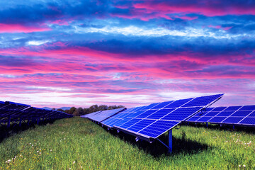 Solar panel on purple sunset sky background. Green grass and cloudy sky. Alternative energy concept