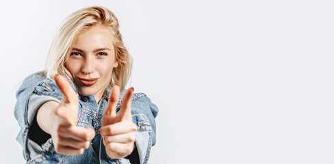 Beautiful young girl fooling around and pointing fingers at screen on gray isolated background