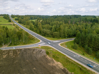 Aerial view from above of highway intersection, green forest and construction site.