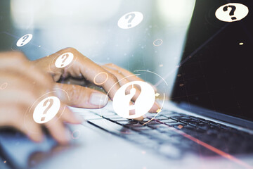 Creative concept of question mark illustration and hands typing on laptop on background. FAQ and...