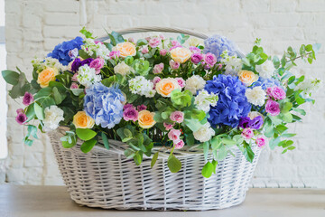Large floral basket with colorful flowers on table at workshop, flower shop. Floristry, holiday, romantic, celebration, handmade and small business concept