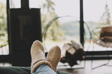 Feet in warm cozy socks on background of modern  fireplace and window with view on mountains