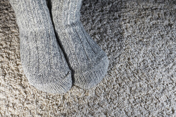 feet in warm knitted socks on a fluffy carpet    
