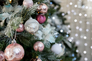Obraz na płótnie Canvas Christmas Decoration. Pink, silver and white Balls on Christmas tree branch. Holiday Card.Christmas toy ball hanging on branch of spruce. New year tree decorated with a garland.Stylish Christmas tree