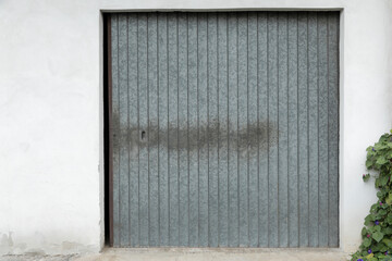 Bright building wall with  garage door with grey closed shutters, metal gate blank with space for text, perfect background