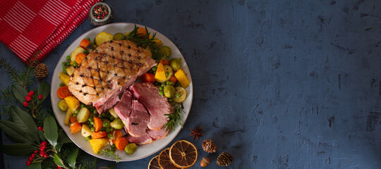Roasted sliced ham with vegetables. Christmas decorations. New Year dinner table. View from above, top studio shot. copy space