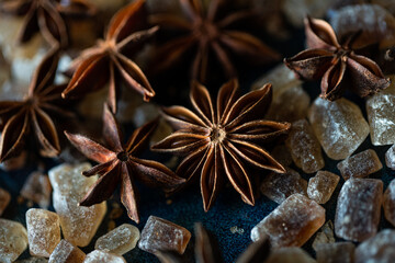 Close up anise stars , brown sugar crystals, and cinnamon sticks on deep blue background.