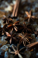 Close up anise stars , brown sugar crystals, and cinnamon sticks on deep blue background.