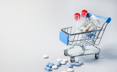 Medicine concept. Various capsules, pills and medicines in a shopping cart on a gray background...