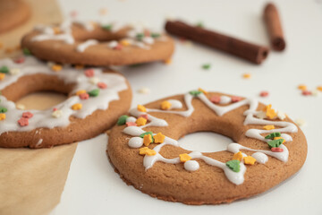 Homemade gingerbread cookies in the form of rings, glazed, yummy Christmas cookies with sprinkles, cinnamon sticks.