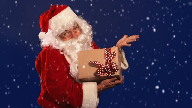 Latin Santa Claus laughing with present in hand in a snowy dark blue background