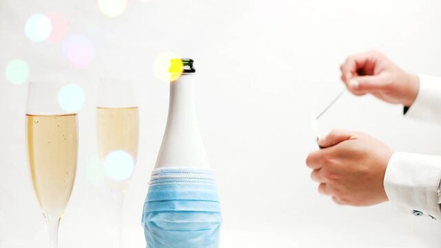 Man in white shirt lighting up a bingala fire Fireworks near poured champane and covid champane bottle to celebrate cristmas or new year