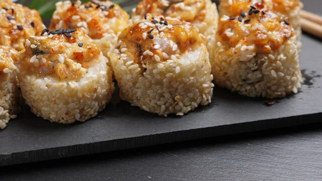 Sushi roll baked eel on black slate plate. Rotate